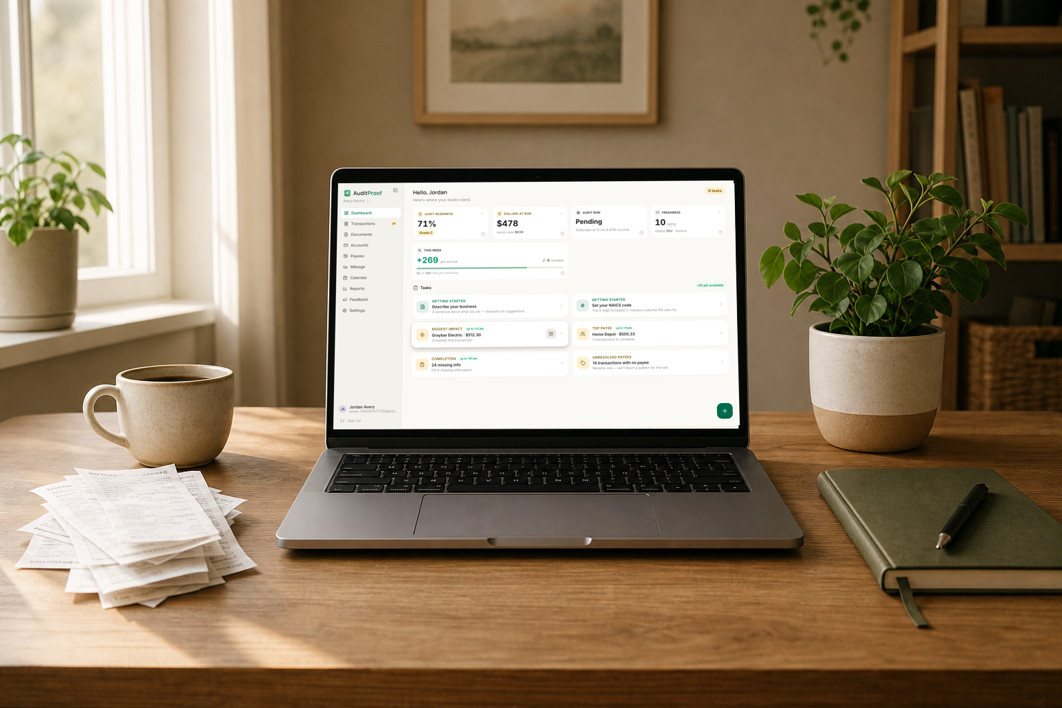 A tidy desk with a laptop showing AuditProof monthly reports beside a stack of receipts